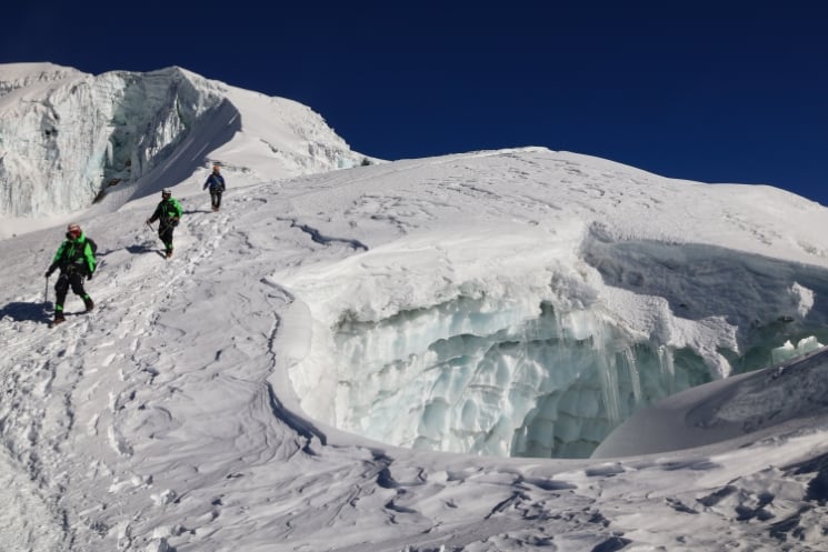 Group of three tight together with a rope above glacier crevasse